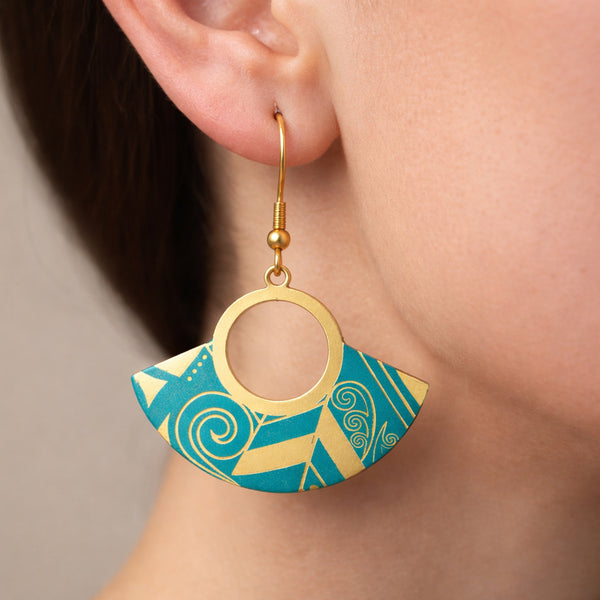 Gold and blue geometric earrings worn by a person